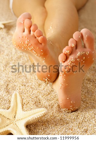 girl's barefoot legs on the sand beach