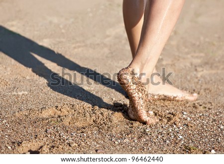 Girl's barefoot legs on the sand beach