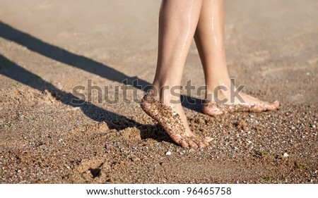 Girl's barefoot legs on the sand beach