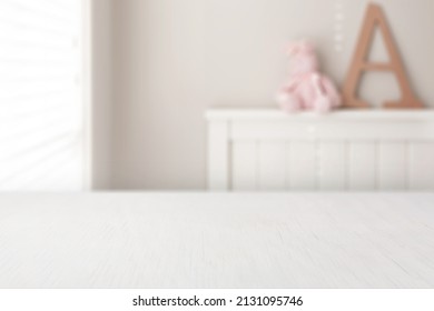 Girls bedroom background. Pink, small teddy bear, sitting on top of a white bed frame next to a giant wooden letter A. 
Place a digital product mockup on the perspective white table. - Shutterstock ID 2131095746