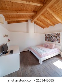 A Girl's Bedroom With White Walls, A Double Bed And A Desk With A Computer. Exposed Wooden Beams. Nobody Inside