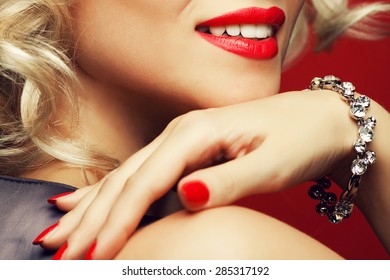 Girl's best friends and femme fatale concept. Marilyn Monroe style. Close up portrait of rich young woman smiling wearing expensive luxurious diamond bracelet. Studio shot