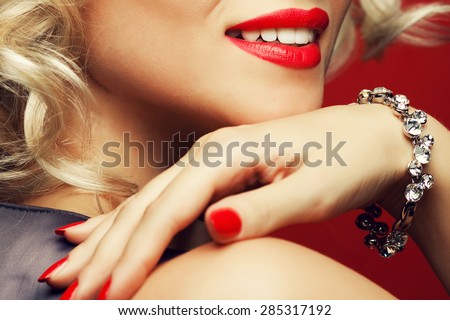 Girl's best friends and femme fatale concept. Marilyn Monroe style. Close up portrait of rich young woman smiling wearing expensive luxurious diamond bracelet. Studio shot