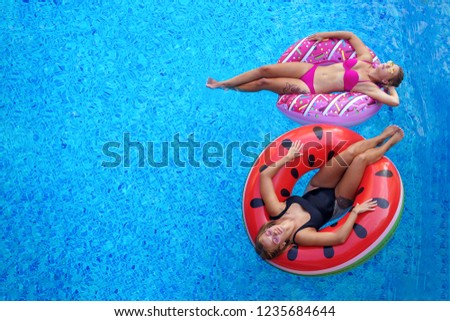 girls in bikini smimming and tanning in pool on the inflatable mattress