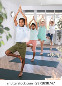 Girls and boys of different nationalities doing yoga together - tree pose