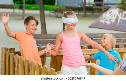 Girls and boys are playing in blindfolders on the playground.