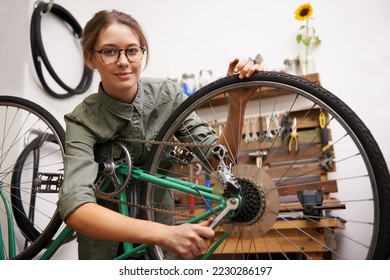 Girls can fix things too. Shot of a young woman looking at the camera while fixing a bicycle.