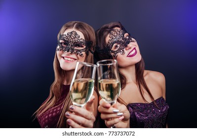 Girls celebrating New Year's eve drinking champagne on masquerade party - Powered by Shutterstock