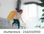 Girls child jumping on home living room couch wearing improvised super hero outfit fancy dress, playing having fun with energetic games, indoors. Discovery kids activities holiday lifestyle.