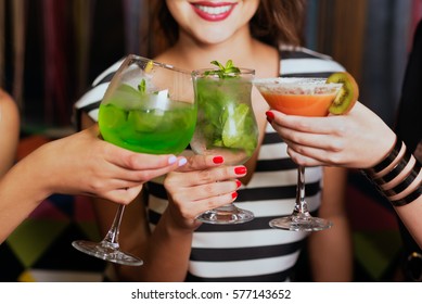 Girls with cocktails toasting against flying colours shot closeup