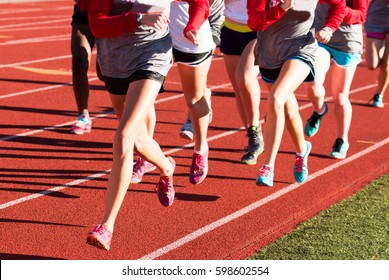 Girls Cross Country Workout Running Intervals Together On A Red Track While Wearing Spikes.