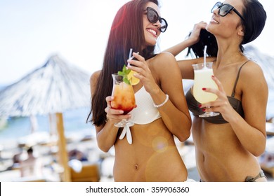 Girls Drinking Cocktails On Beach In Bikinis