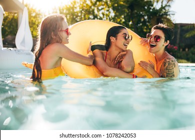 Girls enjoying a day in swimming pool with inflatable ring. Smiling women friends having fun in pool. - Powered by Shutterstock