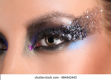 Girl's eye with makeup and colorful crystals. Close up