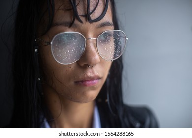 The girl's face, wet from the rain. Her hair and clothes were wet. Glasses fogged up and all the drops of rain. Close-up portrait. - Powered by Shutterstock