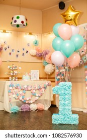 Girl's first Birthday decorations. Party for little girl. Number one on background of beautiful decorated candy bar and balloons. Pink, lilac, mint colors. Decor from paper