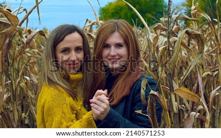 Girls, girlfriends, hugging in a dry corn field.