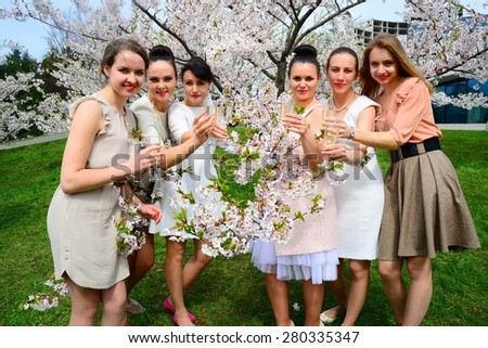 Girls with glass of champagne celebrating in Vilnius sakura's garden.