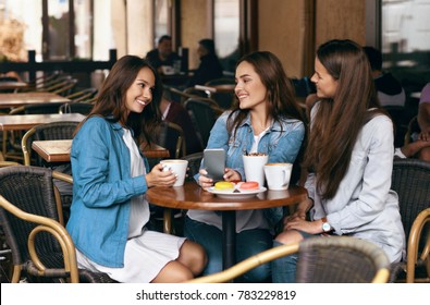 Girls Gossip. Friends With Coffee Speaking In Cafe. Smiling Females Friends Talking And Laughing, Drinking Coffee While Sitting At Table In Coffee Shop. Friendship. High Resolution.