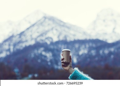 Girl's hand holding a cup of warming beverage with Mountain View - Powered by Shutterstock