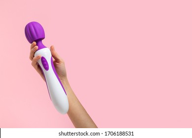 Girl's hand holds a pink massager for sex. Vibrator for masturbation. Dildo for vaginal and clitoral stimulation. Image for sex shop. Sex toys for adults. Massager for the clitoris.