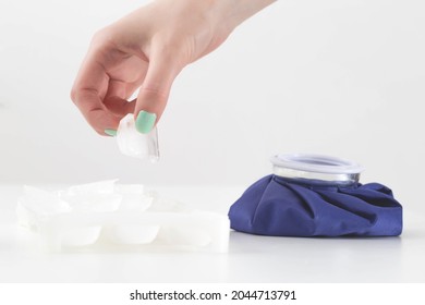 The Girl's Hand Puts A Piece Of Ice Into A Special Medical Bag On A White Background To Relieve Swelling And Inflammation In Case Of Injury And Bruise