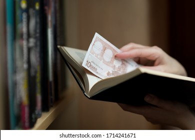 girl's hand puts or takes out savings in euros from a paper book. Savings for a bad time