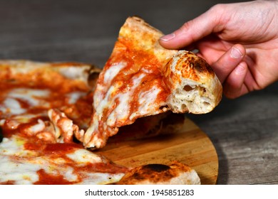 A girl's hand takes a slice of high-dough Neapolitan margherita pizza  based on mozzarella, cheese, buffalo mozzarella, tomato sauce, basil