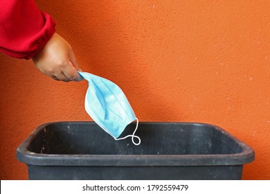 Girl's Hand Throwing Medical Face Mask In The Rubbish In A Park. Single Use Face Mask. Right Way To Throwing Used Face Mask In Bin. Coronavirus Or Covid-19 Concept.