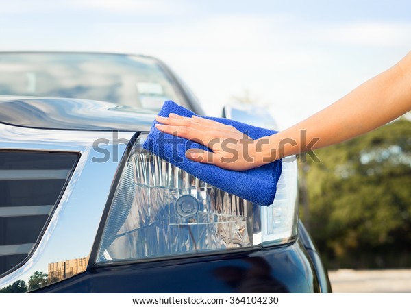 Girl\'s hand wiping on\
car\'s headlight.