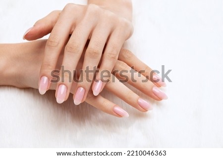 Girl's hands with a beautiful pale pink manicure. In the hands of white fur. the nail extension procedure in a beauty salon. Professional hand care.