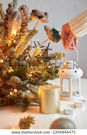 The girl's hands create a Christmas decoration. The girl puts a candlestick with a candle on the table. Holiday home decoration
