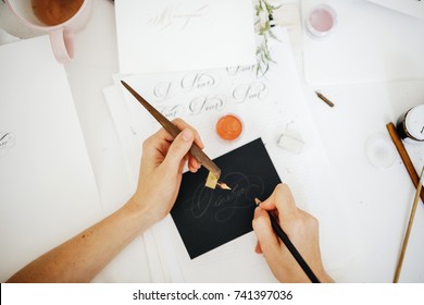 The Girl's Hands Hold A Brush And A Pen For Writing With A Typographical Handwriting. Caligraphy And Lettering.