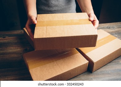 Girl's Hands Holding The Package On The Table