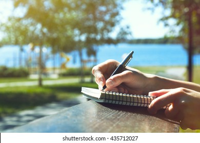 girls hands with pen writing on notebook in park - Shutterstock ID 435712027