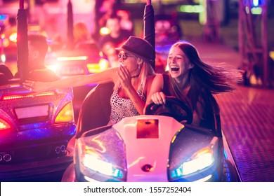 Girls having fun in electric bumper car in amusement park