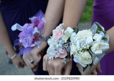 girls holding their hands together showing off corsages for prom, pretty purple pink cream flowers with bows - Powered by Shutterstock