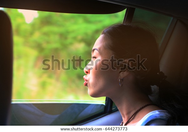 Girl\'s journey.The face is happy in car.While cars\
are running along the road in the jungle mountains.With a long way\
dark time The evening when the sun is shining orange Fast cars\
Soften the focus.