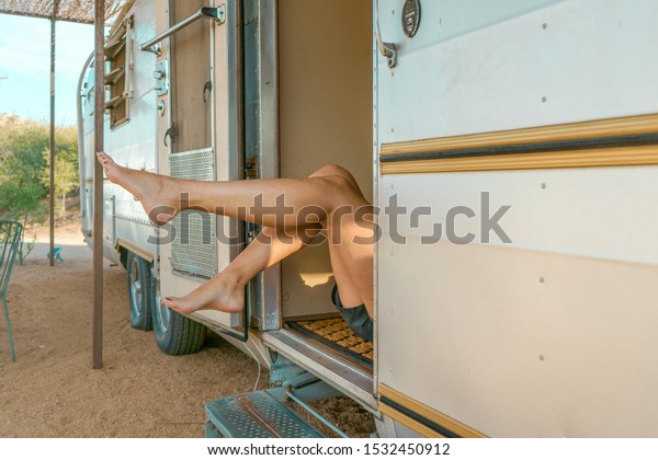 Girl\'s legs inside a van. White steel camper\
van. Traveler concept. Desert route. \
