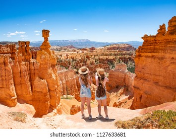 Girls on vacation hiking trip. Friends standing next to Thor's Hammer hoodoo on top of  mountain looking at beautiful view. Bryce Canyon National Park, Utah, USA
