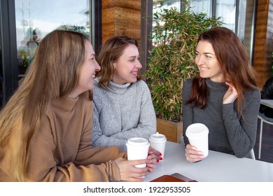 girls, people,  communication and friendship concept - smiling young women drinking coffee or tea and gossiping at outdoor cafe