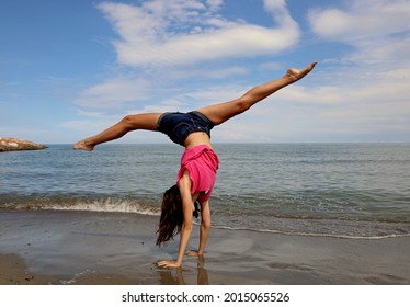 girls performing difficult rhythmic gymnastics exercise called walkover by the sea in summer - Shutterstock ID 2015065526
