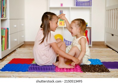 Girls play and have fun together in the children's room on the floor on orthopedic massage mats. Droll kids playing and laughing - Shutterstock ID 2150513495