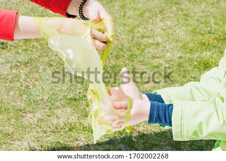 Girls play with a sticky mass of green in the street