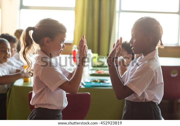 Girls playing\
clapping game in school\
canteen