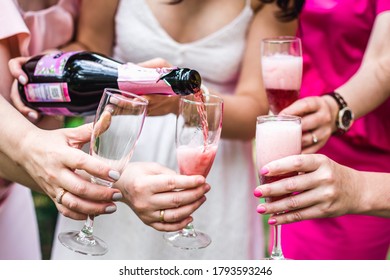 Girls Pour Pink Champagne Into Glasses
