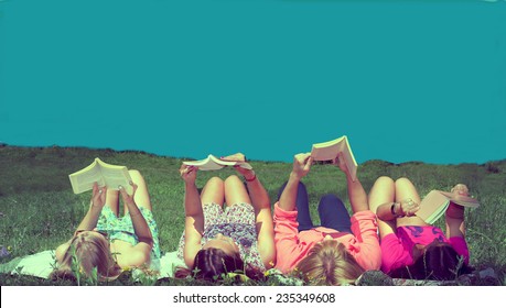 Girls Reading Books Lying On The Meadow Enjoying Sunshine And Blue Sky In The Summer Time Vintage Look Filtered Image