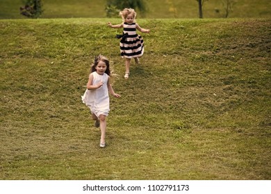 Girls Run From Hill On Green Grass On Summer Day On Natural Landscape. Energy, Energizer, Resilience Concept. Children Playing, Sport, Activity, Fun, Leisure.