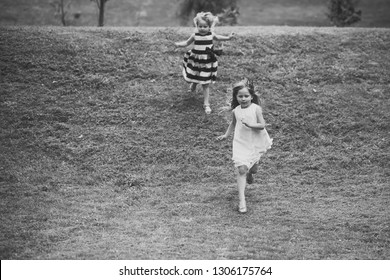 Girls Run From Hill On Green Grass On Summer Day On Natural Landscape. Energy, Energizer, Resilience Concept. Children Playing, Sport, Activity, Fun, Leisure.