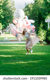 Girls Running In The Park. She's Wearing A Pink Dress And Carrying A Bunch Of Giant Balloons.